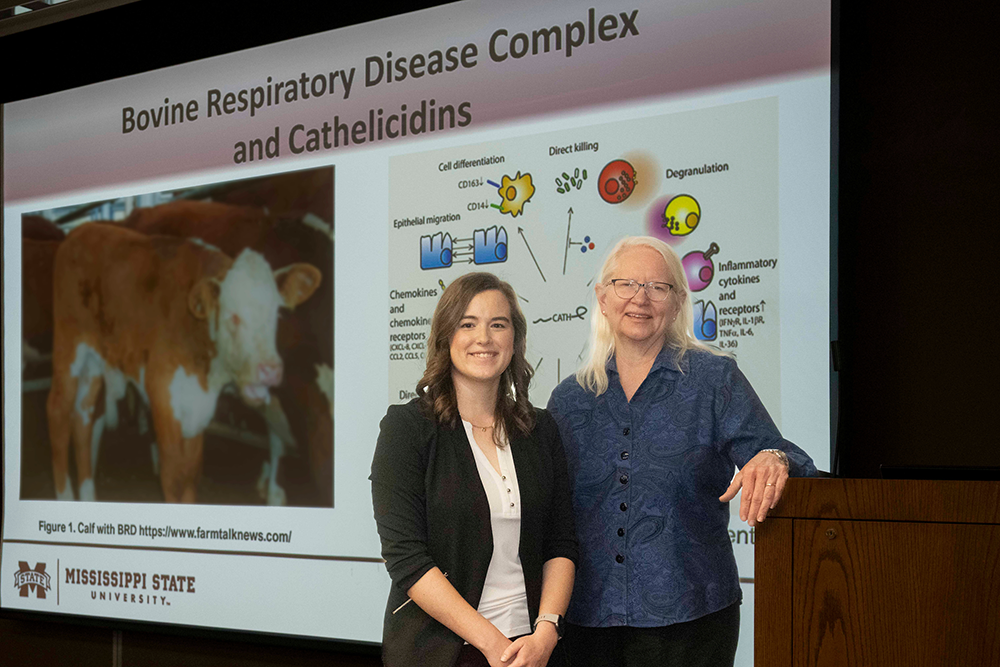 Two women standing in front of a presentation