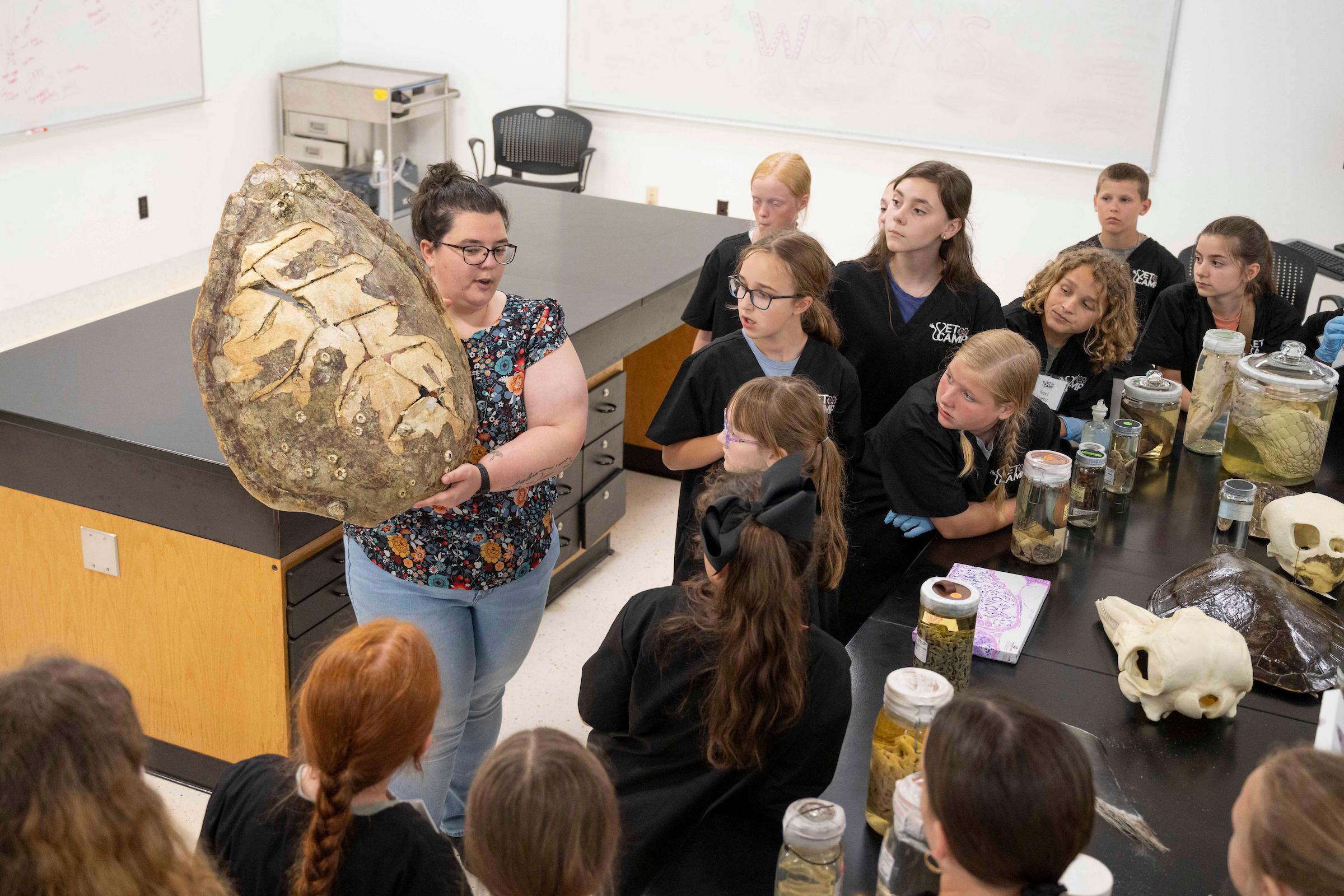 A teacher holds a turtle shell in a class full of students.