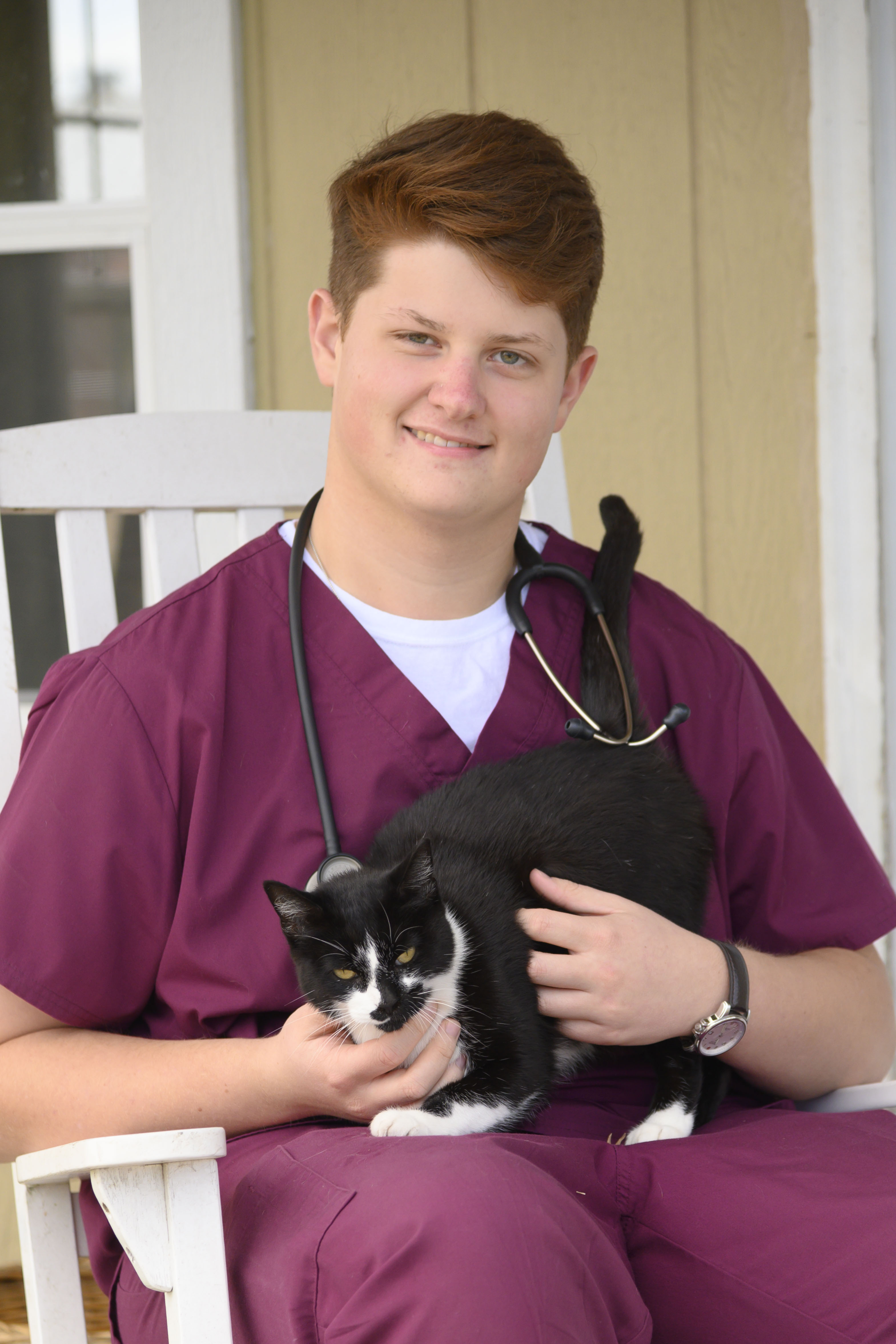 A veterinary student poses with a cat in a rocking chair