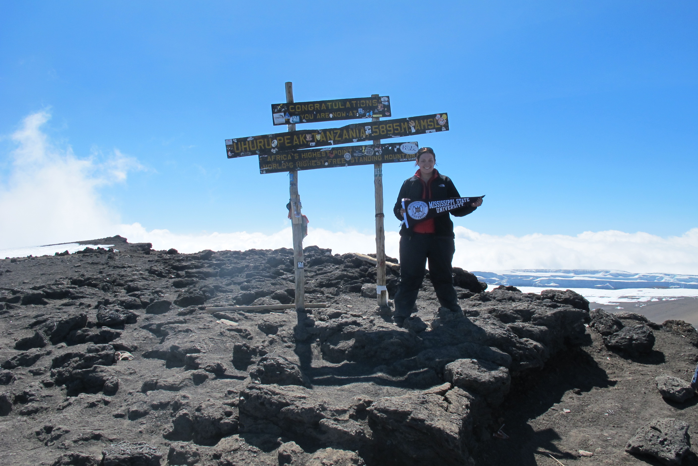 A student poses on top of a mountain