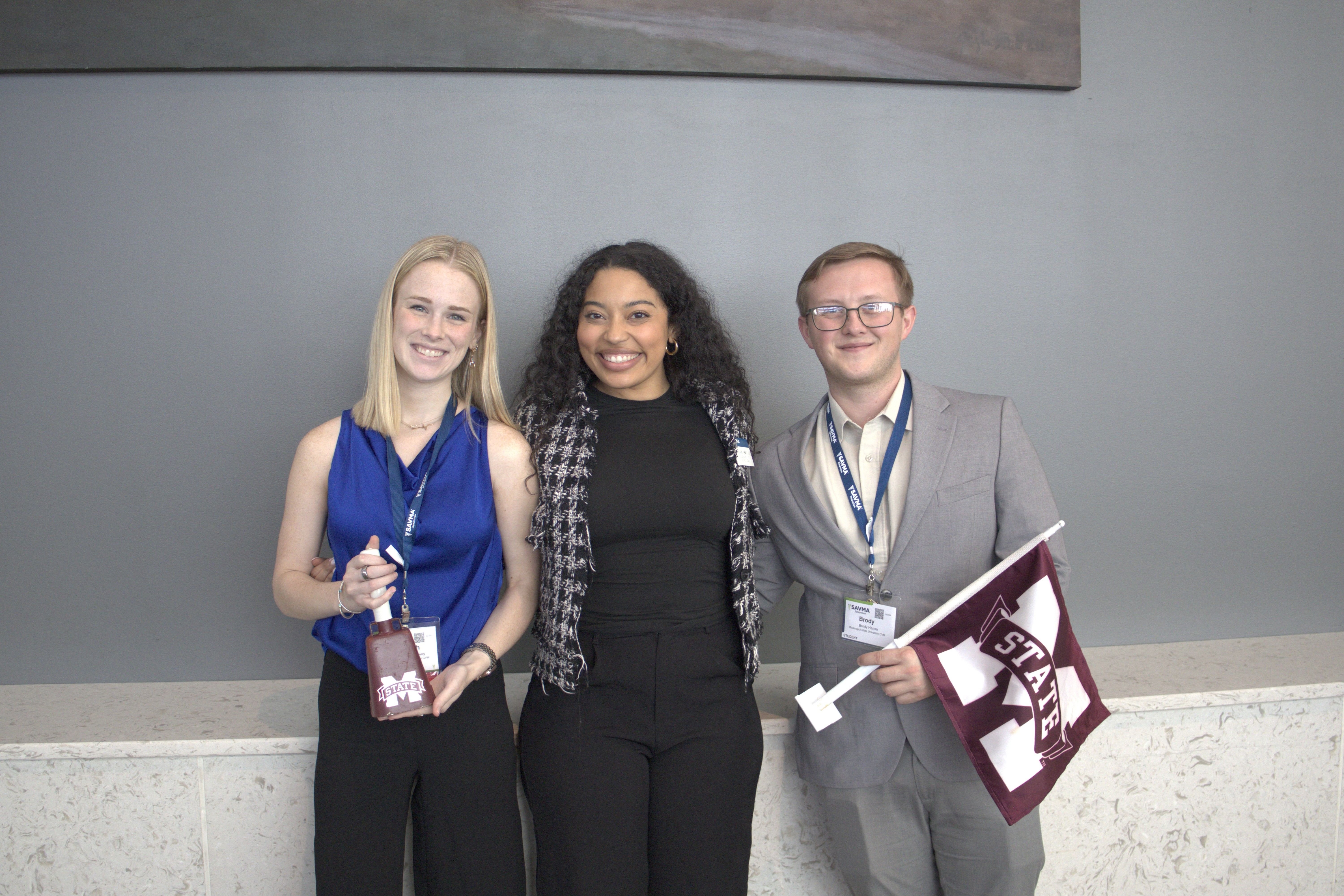 Three MSU students. One holding a cowbell. Another holding a MSU flag.