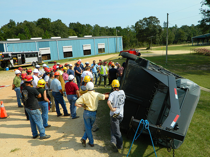 People observe and help as a large animal trailer is turned over