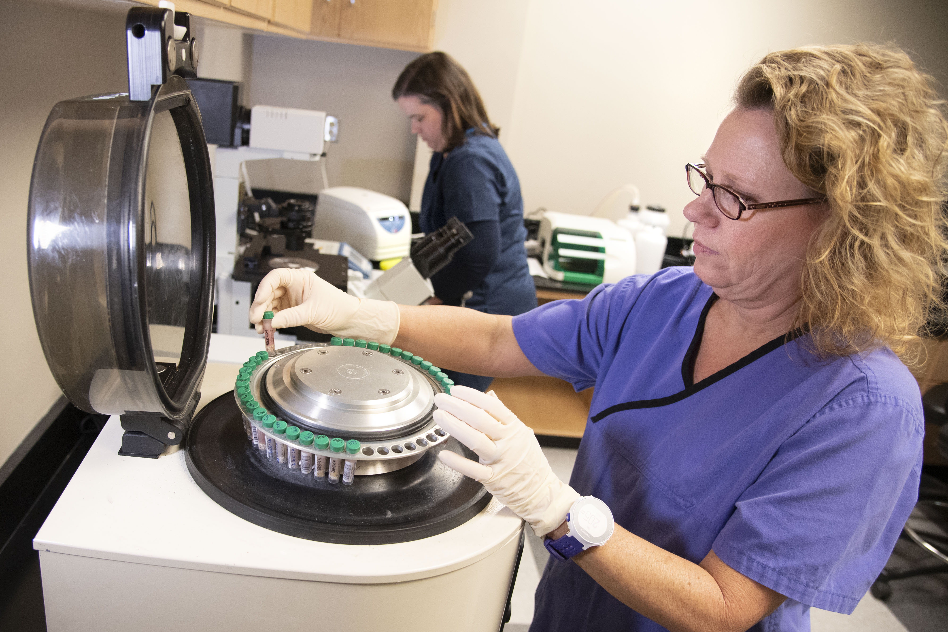 A lab technician places samples in a research machine