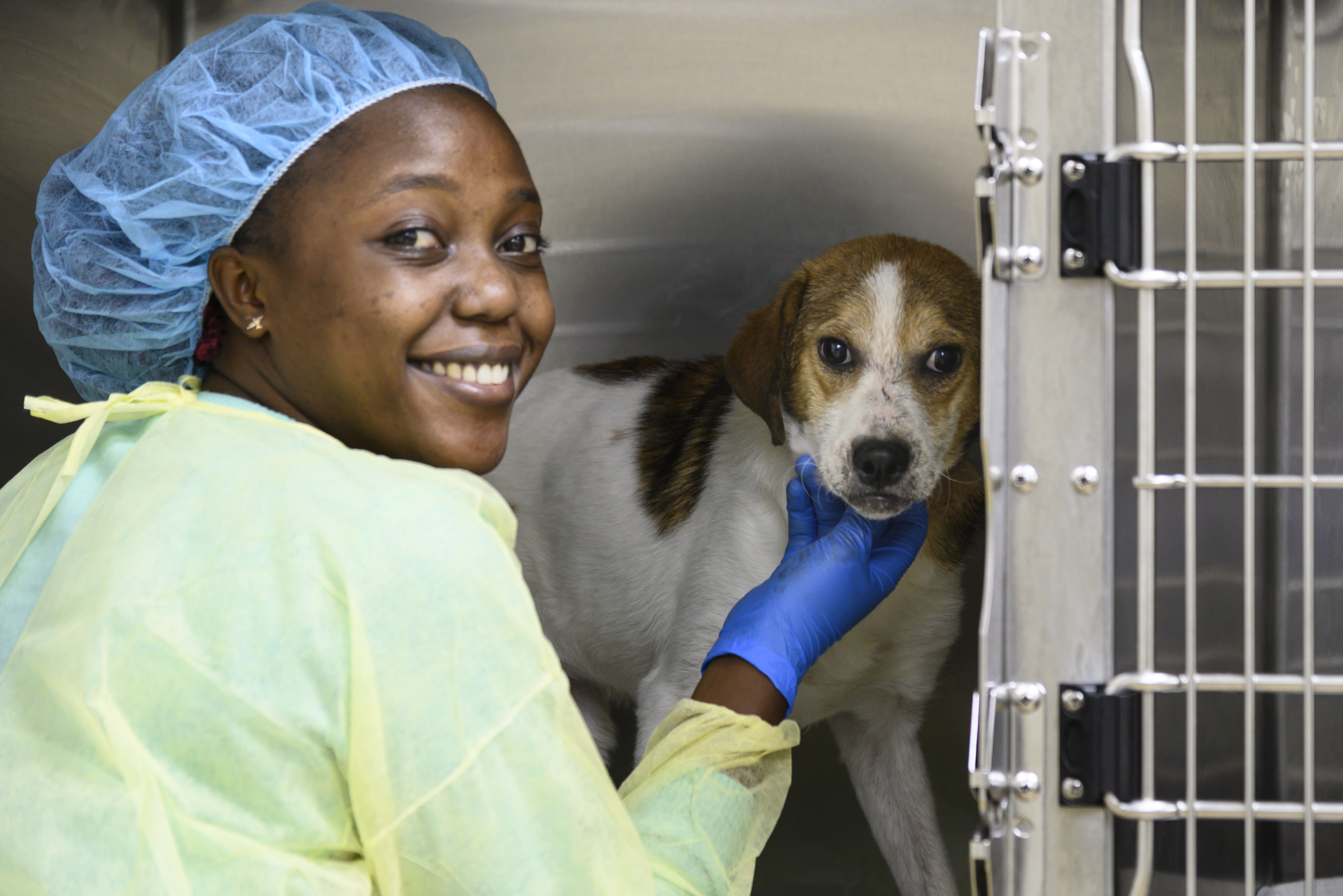 A student in scrubs poses with a dog 