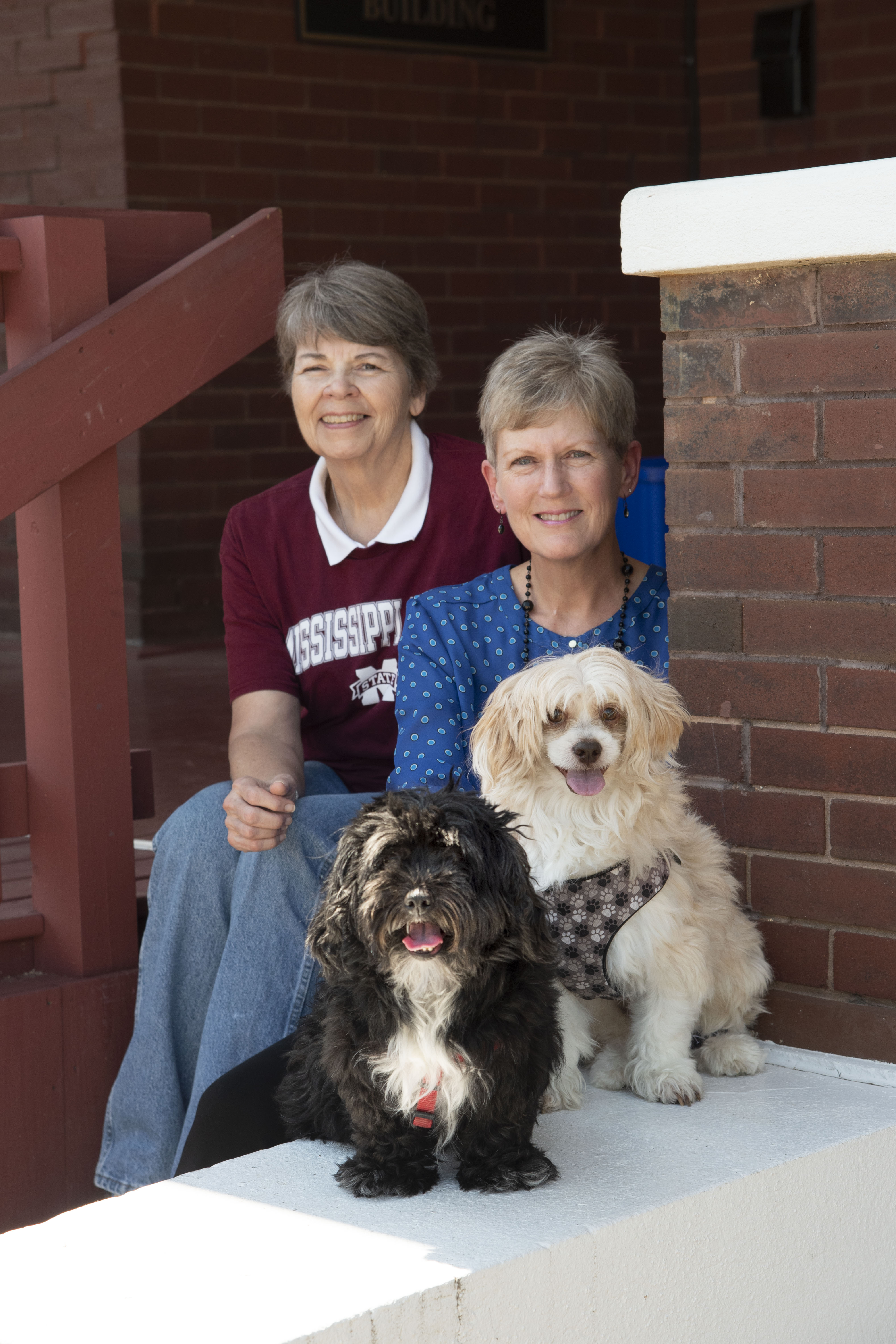 Two women pose with two dogs